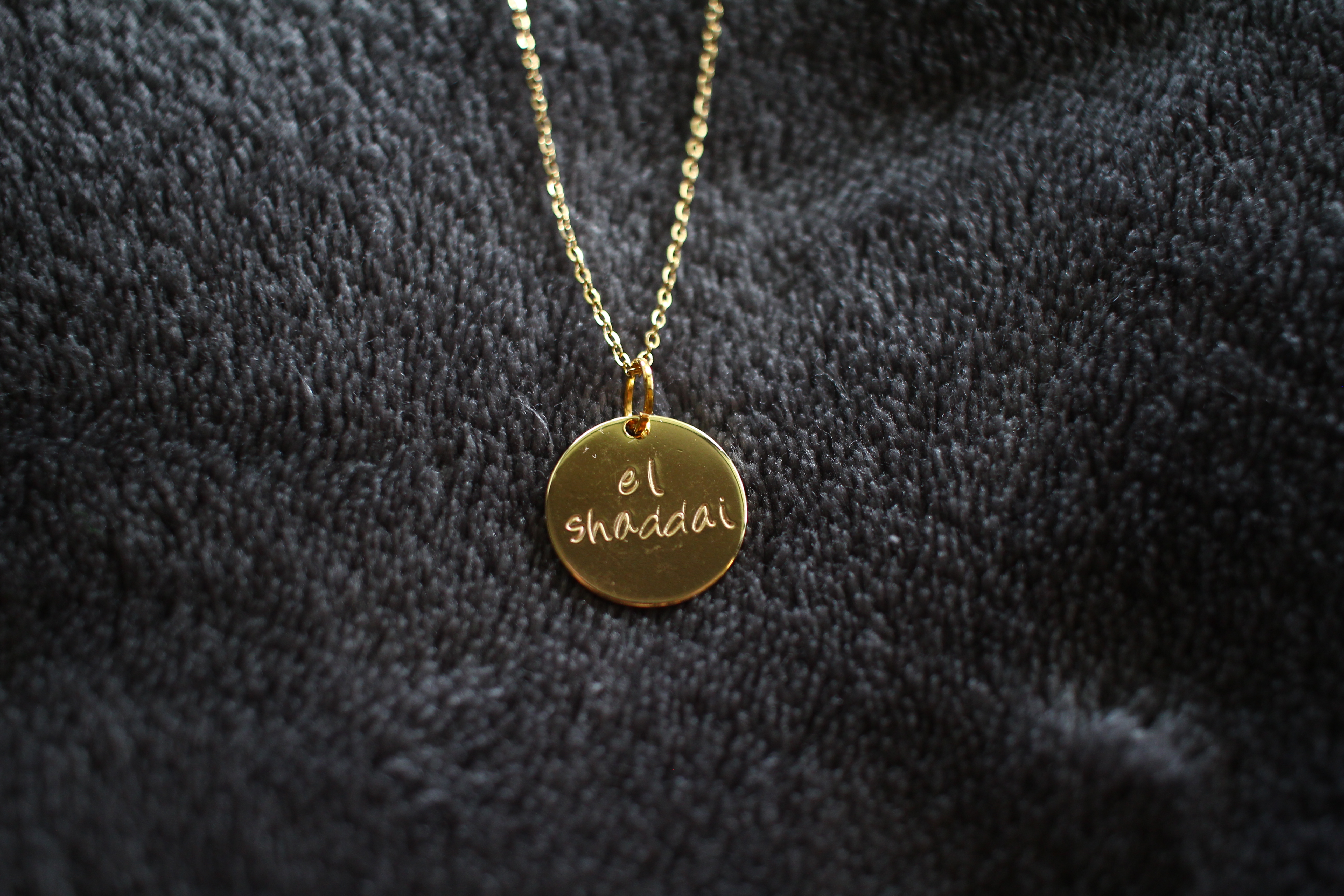 Gold necklace with 'El Shaddai' written on it